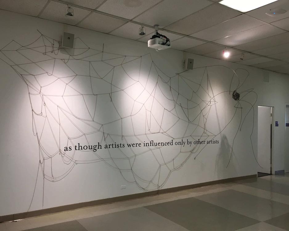 shot of wall covered in yarn web with vinyl text